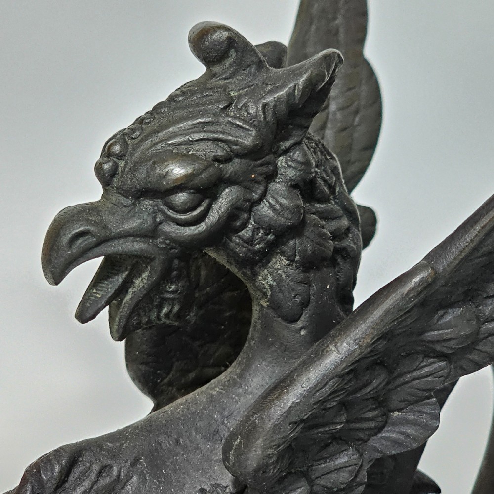 A pair of heavy dark bronze chambersticks featuring mythical griffin figures holding candle nozzles. View XI