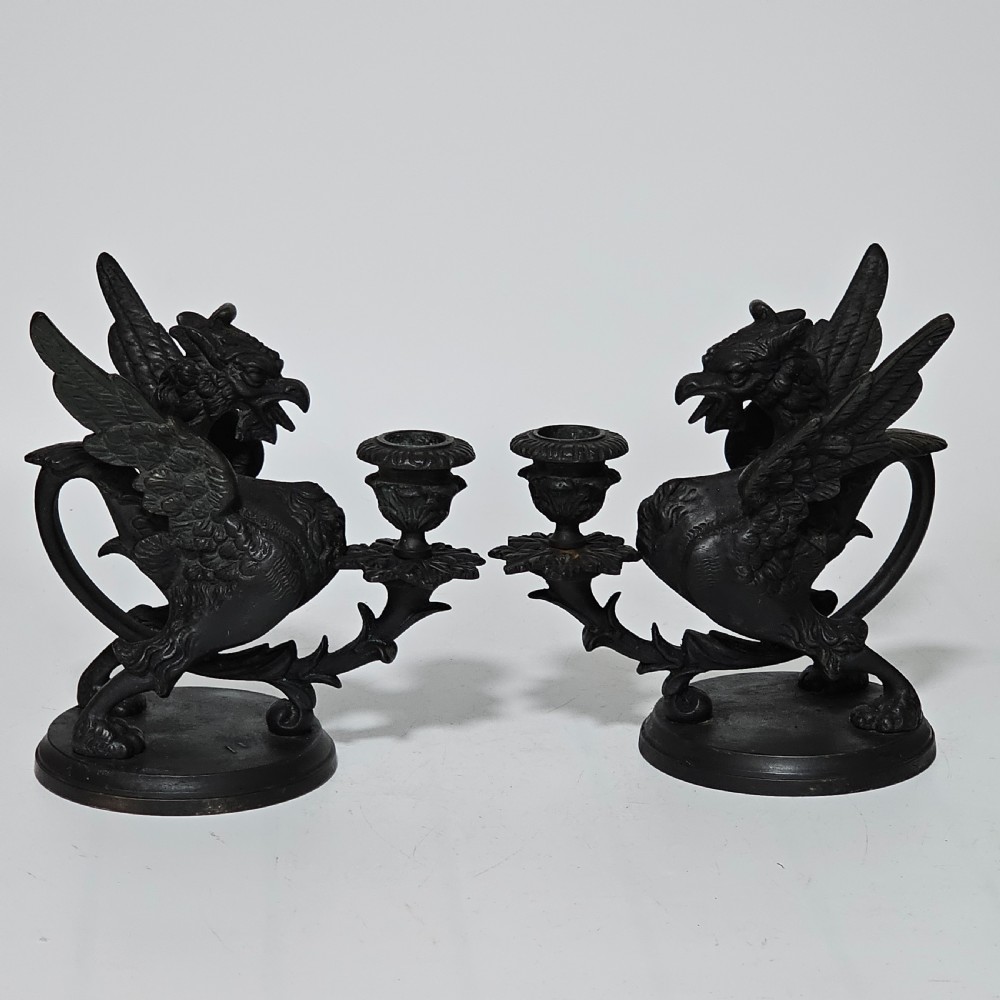 A pair of heavy dark bronze chambersticks featuring mythical griffin figures holding candle nozzles. View XIII