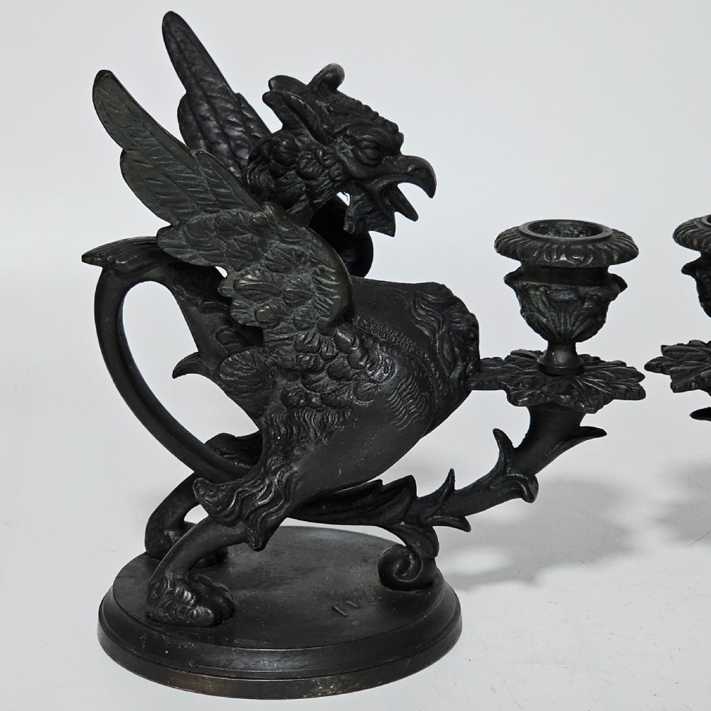 A pair of heavy dark bronze chambersticks featuring mythical griffin figures holding candle nozzles. View XV