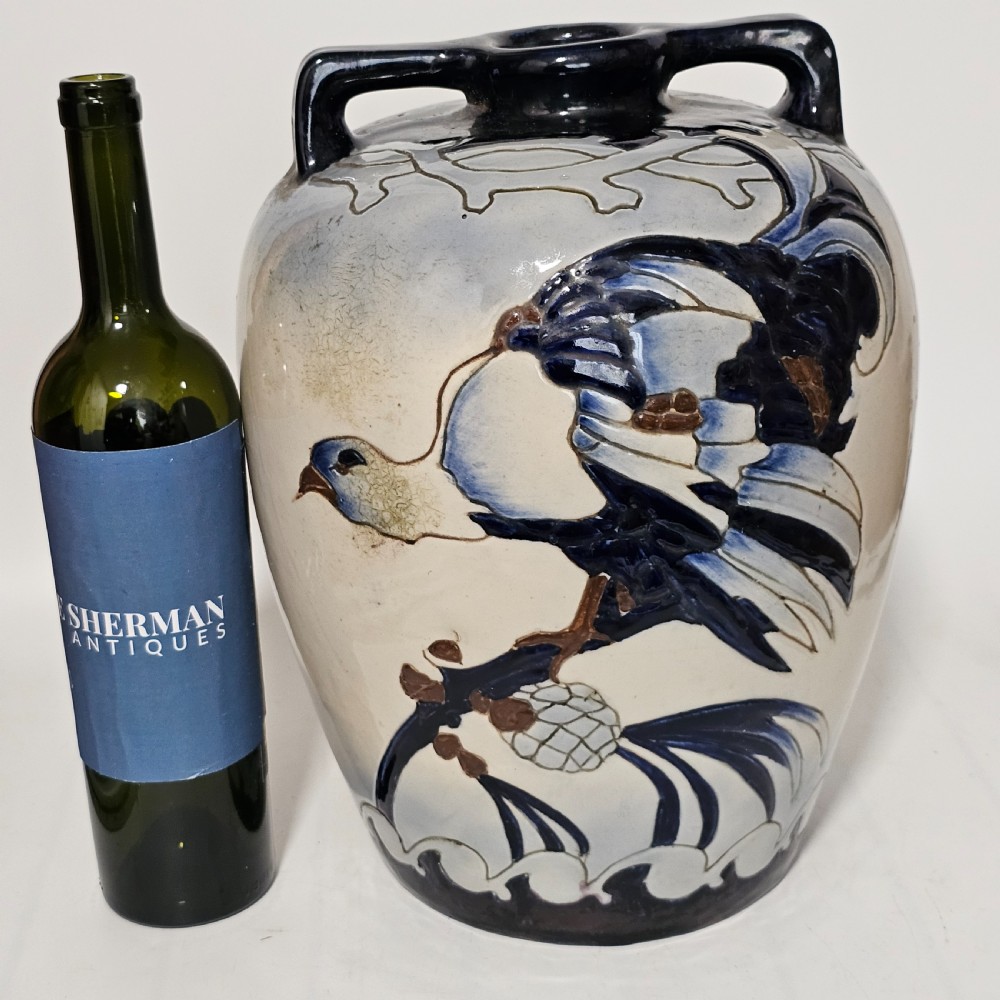 A twin-handled cream ceramic Amphora vase decorated with a stylized bird motif in blue and dark glazes. View III