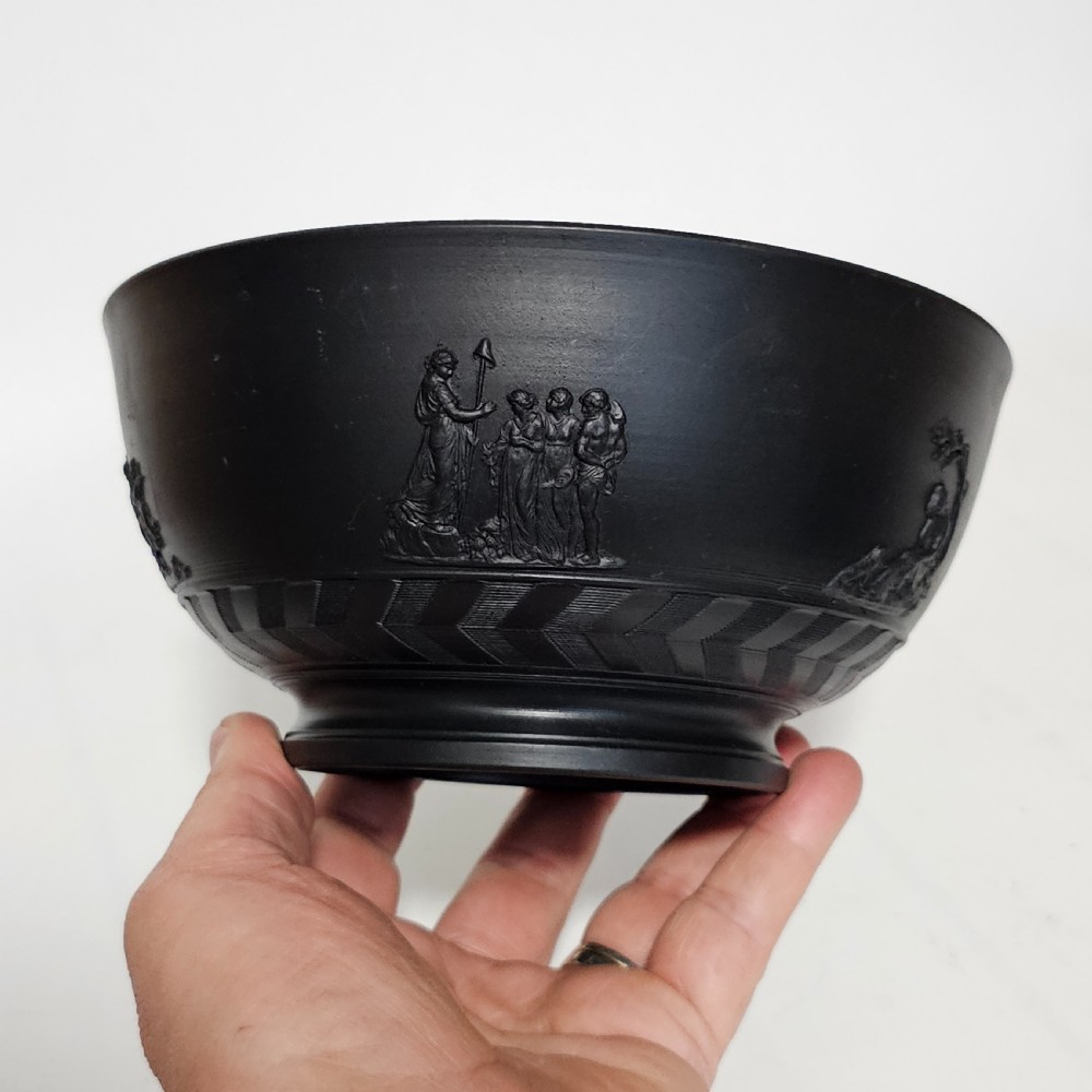 An antique matte black basalt stoneware bowl featuring classical figures in relief around the body and an engine-turned border above the circular foot. View III