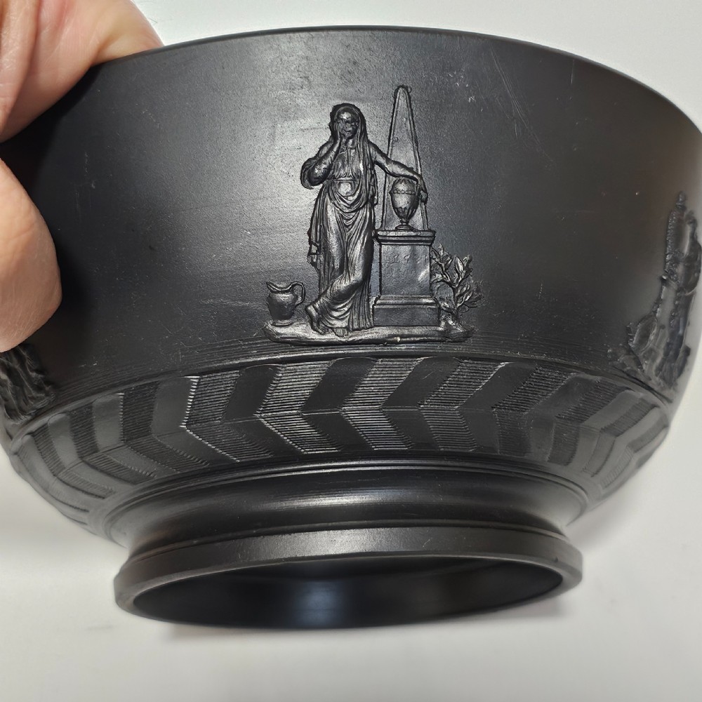 An antique matte black basalt stoneware bowl featuring classical figures in relief around the body and an engine-turned border above the circular foot. View V