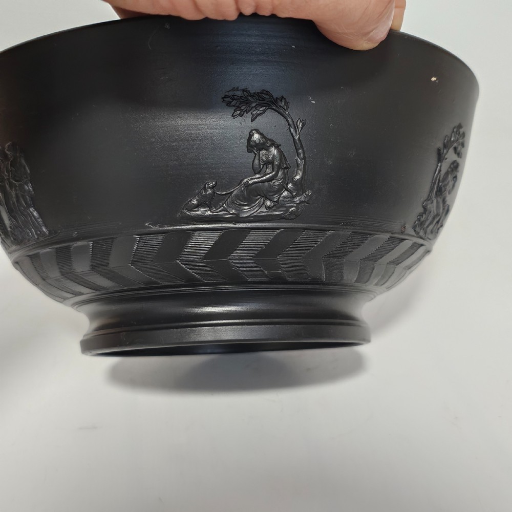 An antique matte black basalt stoneware bowl featuring classical figures in relief around the body and an engine-turned border above the circular foot. View IX