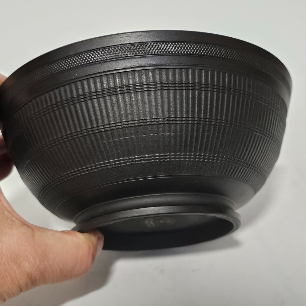 An 18th-century matte black basalt stoneware bowl featuring intricate engine-turned reeded and diced patterns around the exterior.