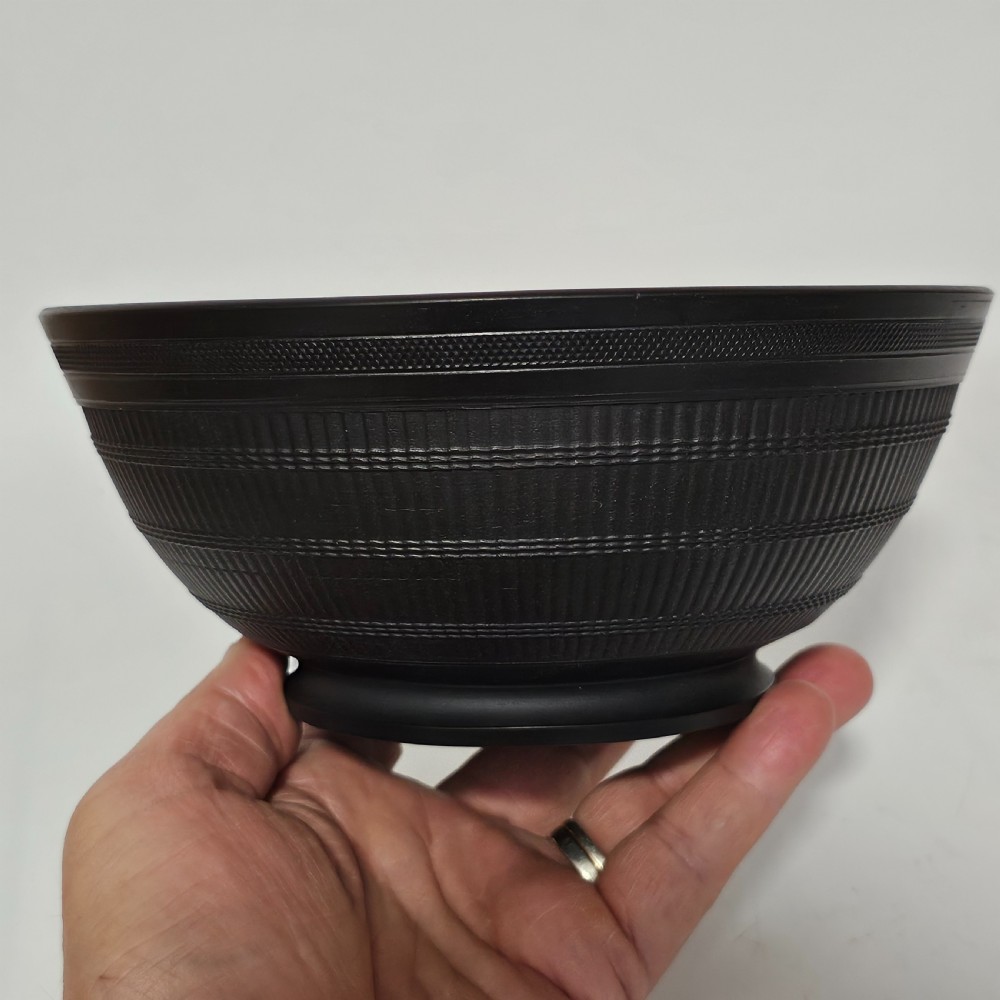 An 18th-century matte black basalt stoneware bowl featuring intricate engine-turned reeded and diced patterns around the exterior. View IX
