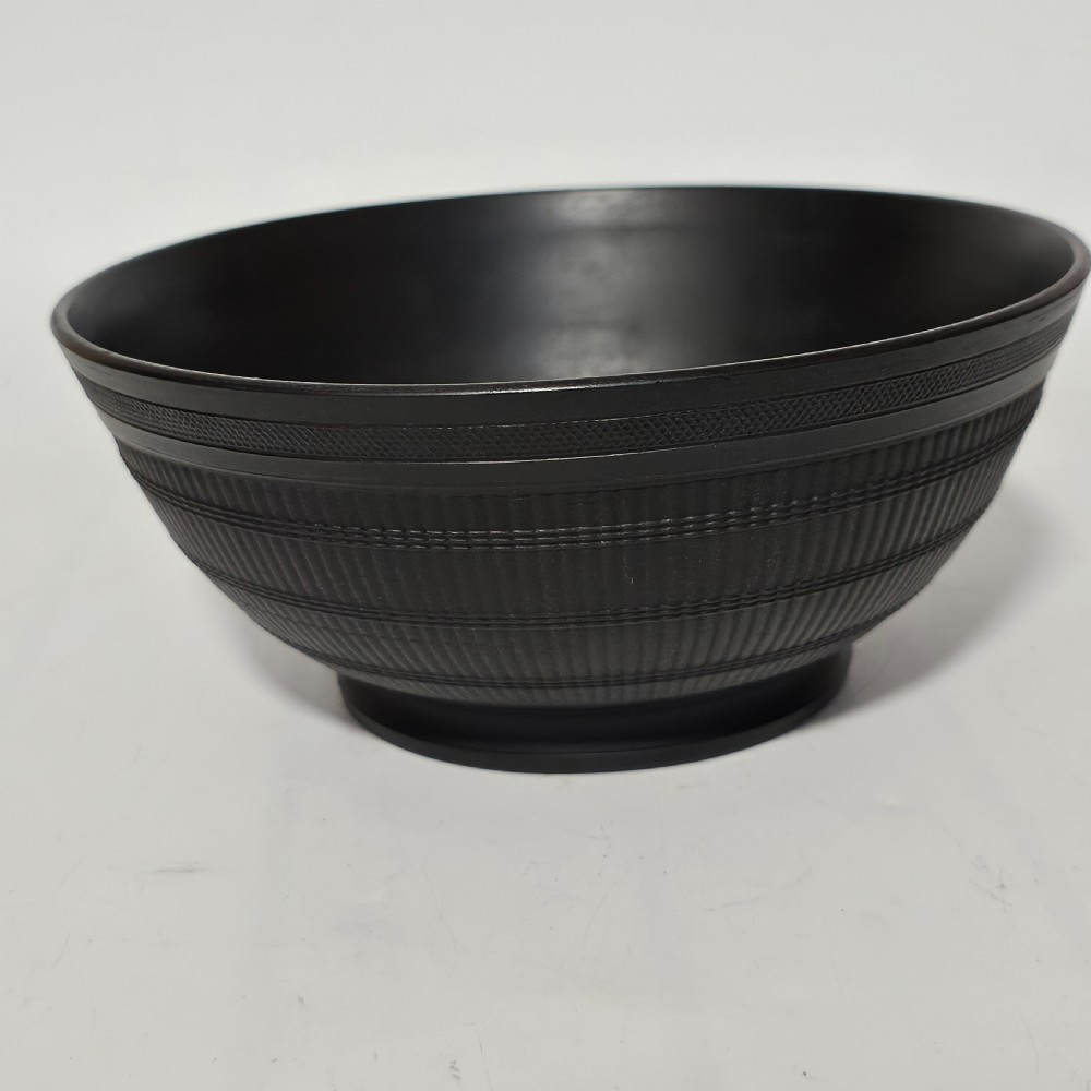 An 18th-century matte black basalt stoneware bowl featuring intricate engine-turned reeded and diced patterns around the exterior. View X