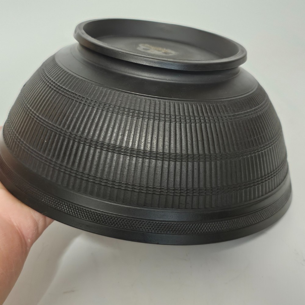 An 18th-century matte black basalt stoneware bowl featuring intricate engine-turned reeded and diced patterns around the exterior. View XI