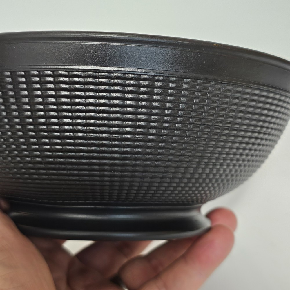 A large matte black basalt stoneware bowl with a textured pattern around the lower body and a circular foot. View II