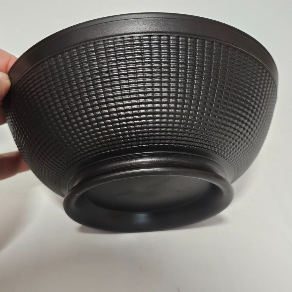 A large matte black basalt stoneware bowl with a textured pattern around the lower body and a circular foot. View IV