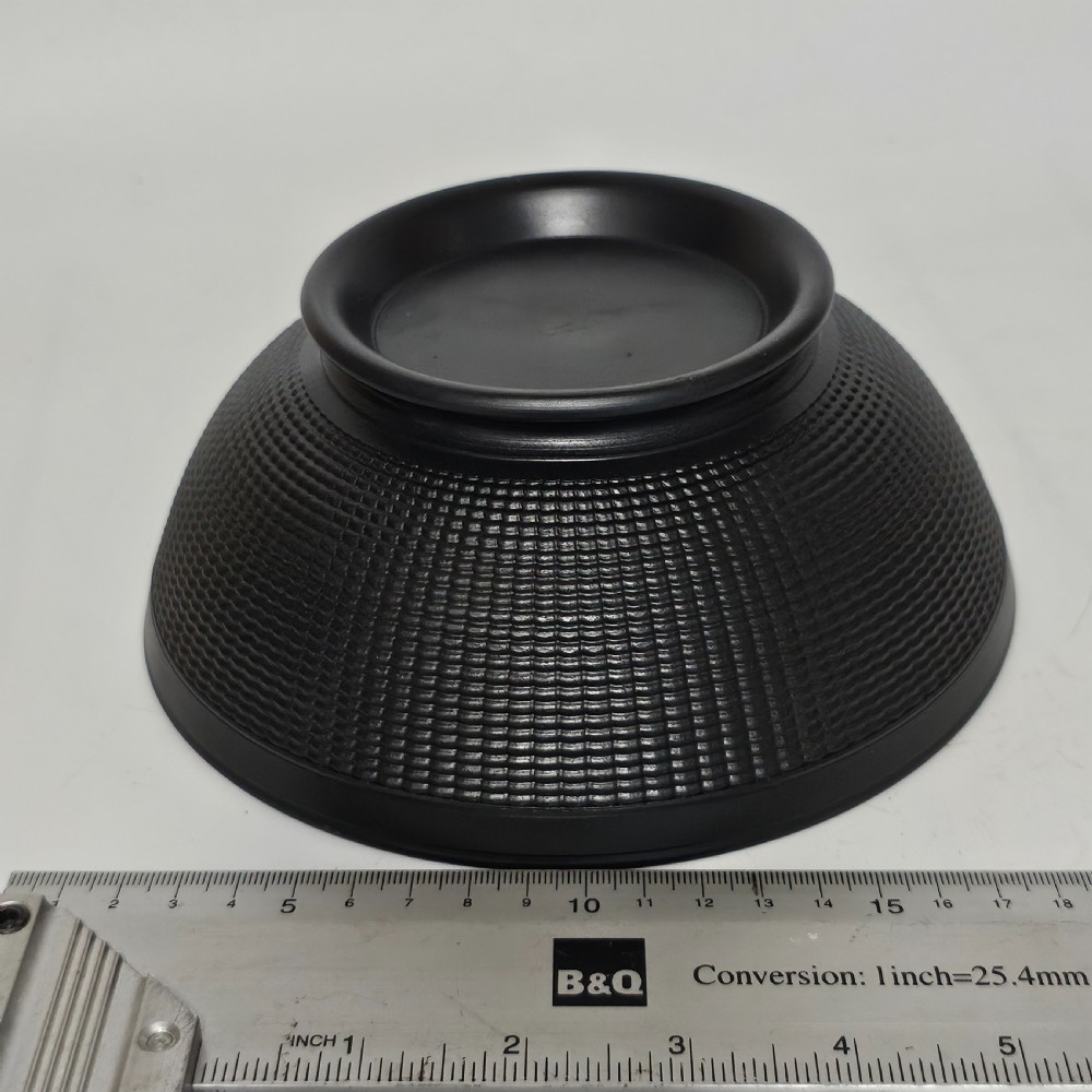 A large matte black basalt stoneware bowl with a textured pattern around the lower body and a circular foot. View V
