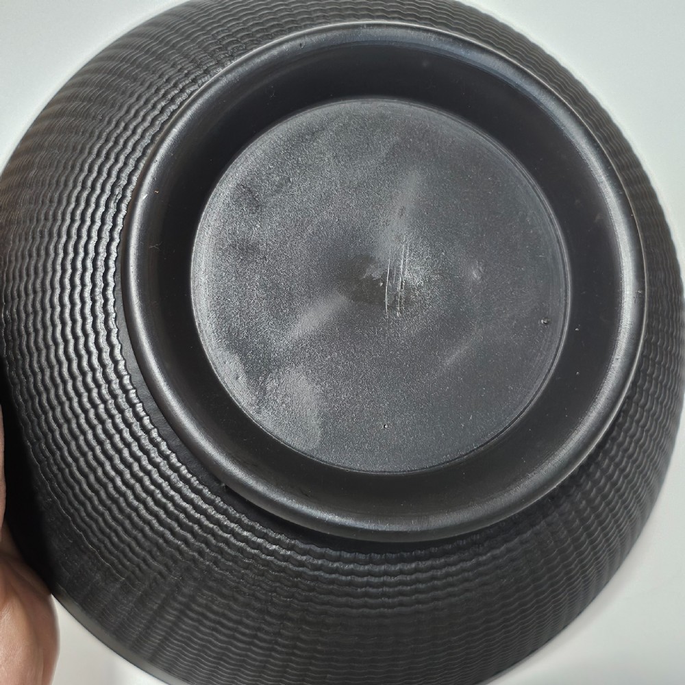A large matte black basalt stoneware bowl with a textured pattern around the lower body and a circular foot. View VI