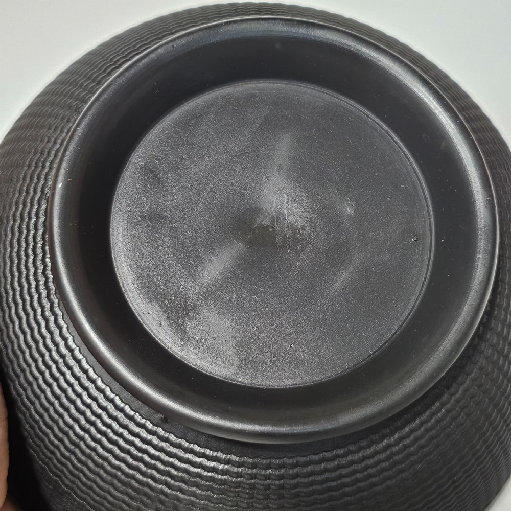A large matte black basalt stoneware bowl with a textured pattern around the lower body and a circular foot. View VII
