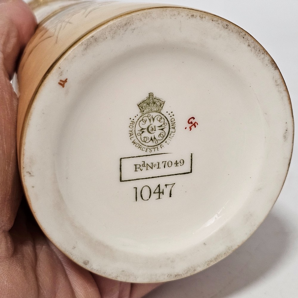 A Royal Worcester blush ivory porcelain ewer featuring hand-painted floral motifs, a gilt textured handle, and raised gold blossom decoration on the neck. View VI