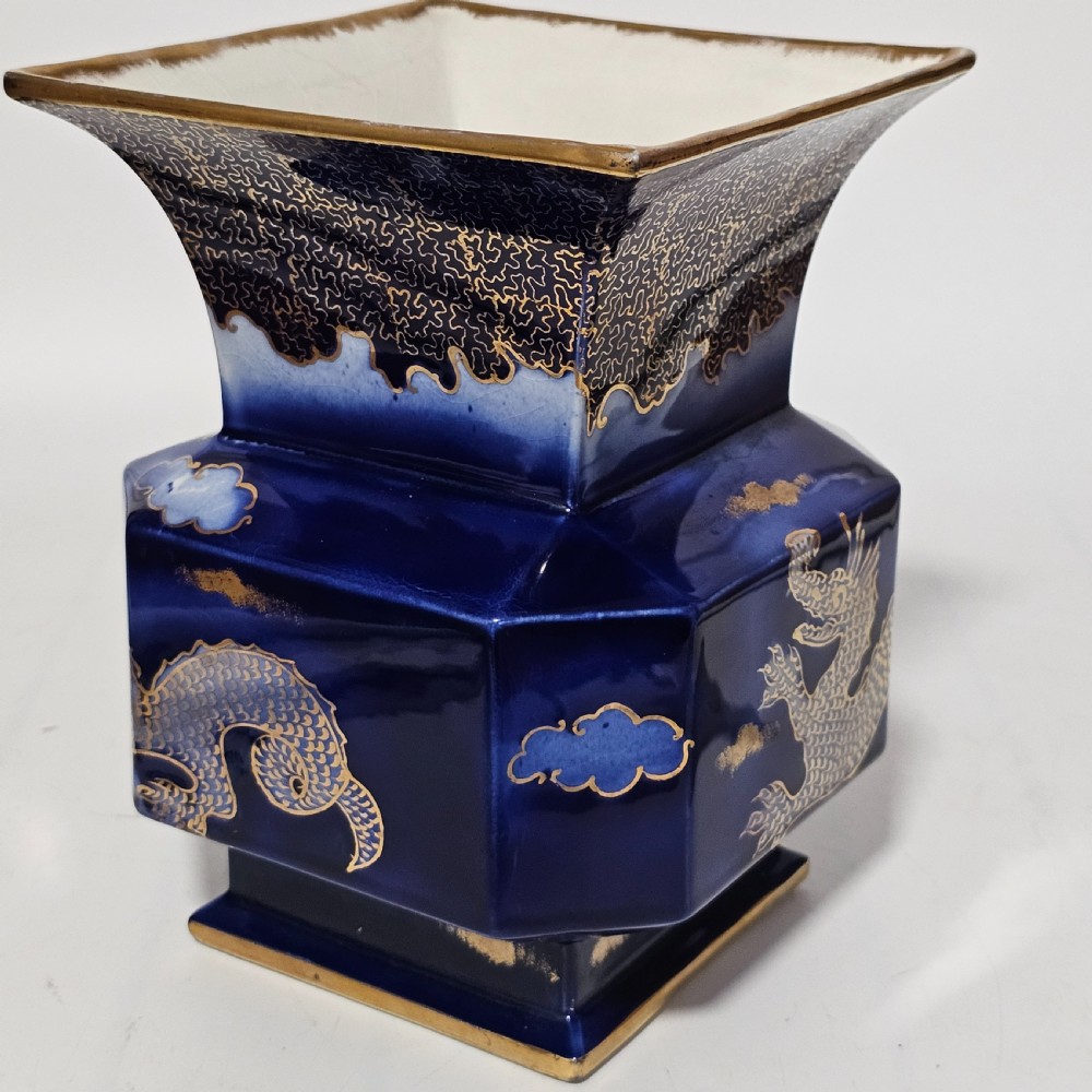 A flared hexagonal cobalt blue porcelain vase decorated with a gilded dragon motif and gold rim. View II
