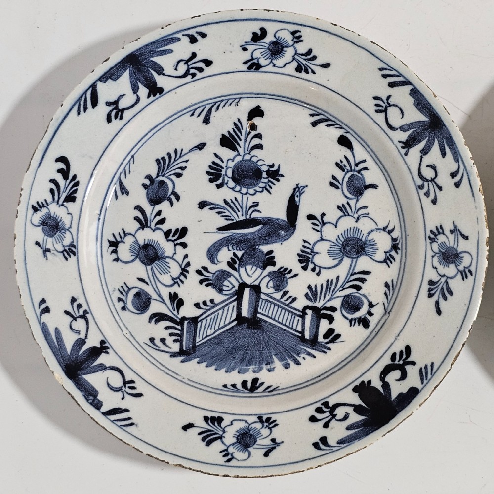A pair of round antique Delft ceramic plates featuring hand-painted blue and white bird and floral motifs on a white tin-glazed background. View II