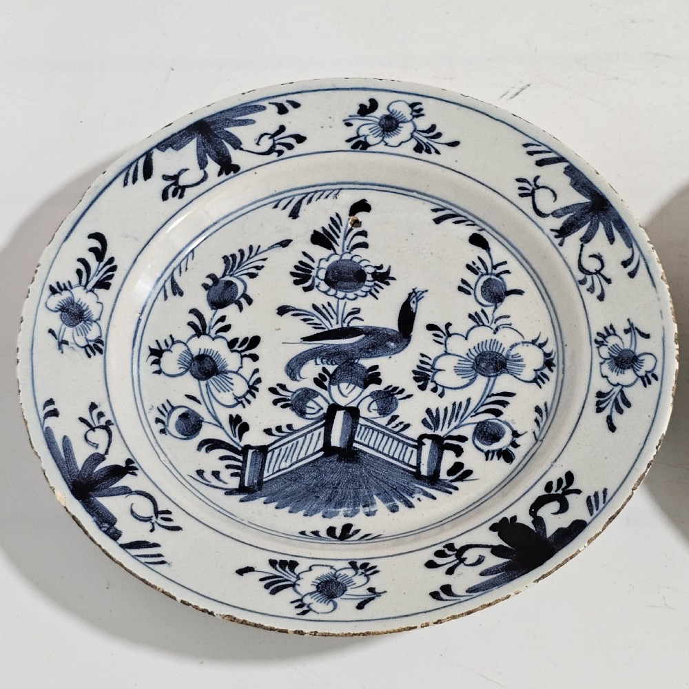 A pair of round antique Delft ceramic plates featuring hand-painted blue and white bird and floral motifs on a white tin-glazed background. View III