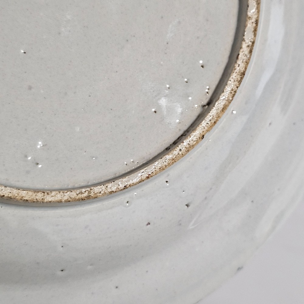 A pair of round antique Delft ceramic plates featuring hand-painted blue and white bird and floral motifs on a white tin-glazed background. View VII