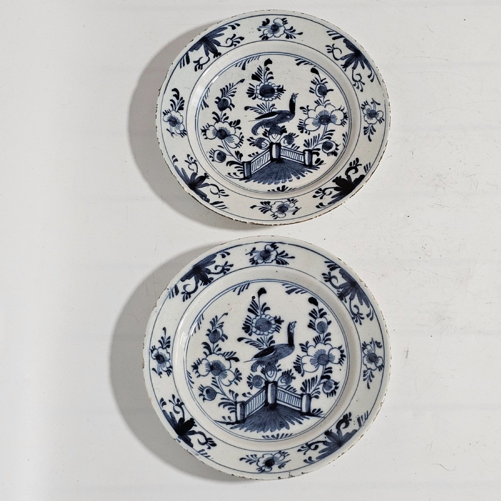 A pair of round antique Delft ceramic plates featuring hand-painted blue and white bird and floral motifs on a white tin-glazed background. View VIII