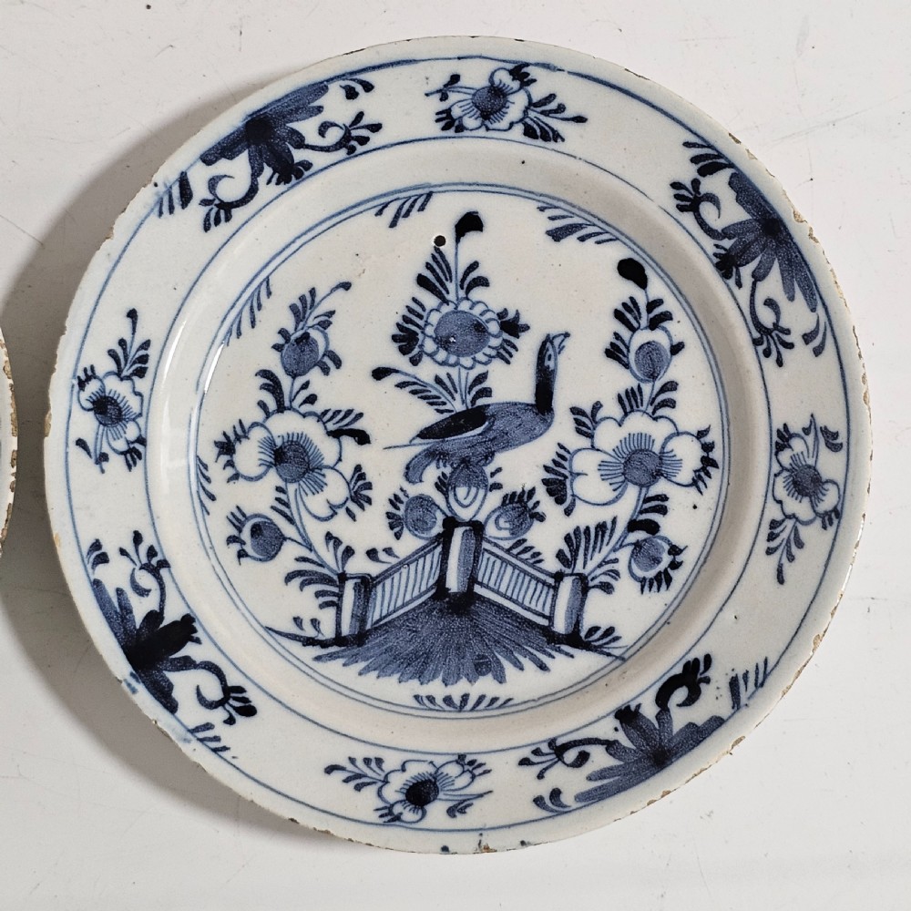 A pair of round antique Delft ceramic plates featuring hand-painted blue and white bird and floral motifs on a white tin-glazed background. View XI