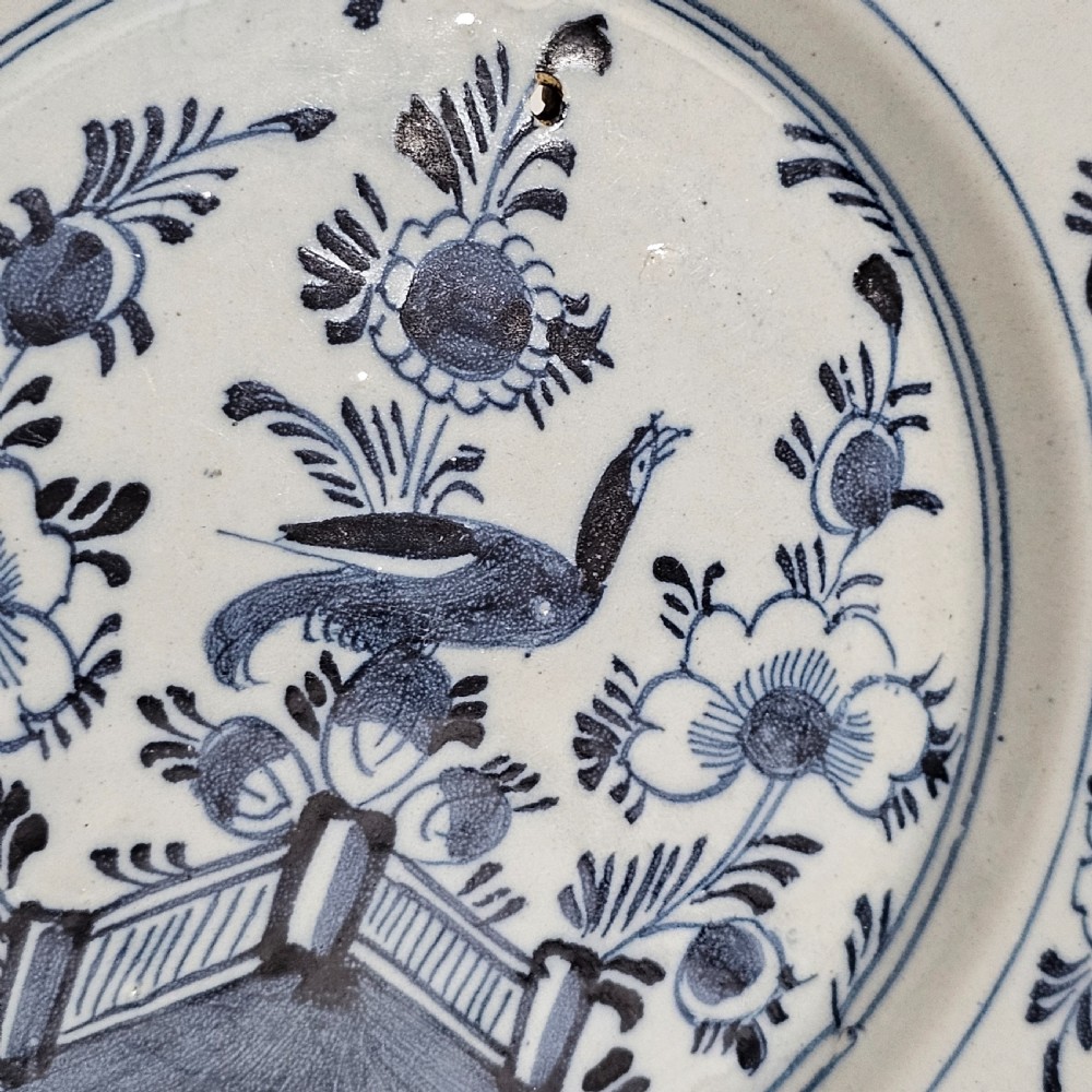 A pair of round antique Delft ceramic plates featuring hand-painted blue and white bird and floral motifs on a white tin-glazed background. View XII