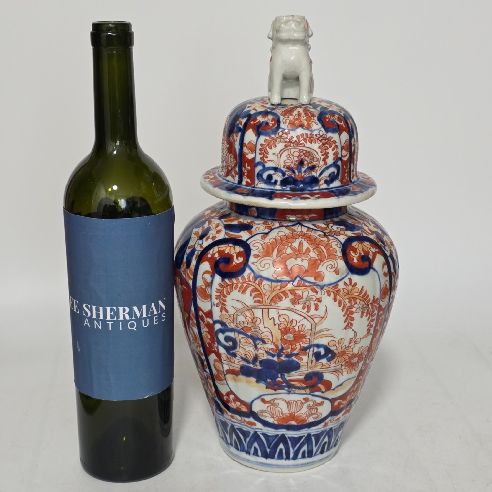 A 19th-century Japanese Imari porcelain covered jar decorated with cobalt blue and rust red floral panel motifs, topped with a sculpted foo dog finial lid. View II