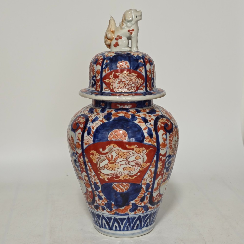 A 19th-century Japanese Imari porcelain covered jar decorated with cobalt blue and rust red floral panel motifs, topped with a sculpted foo dog finial lid. View V