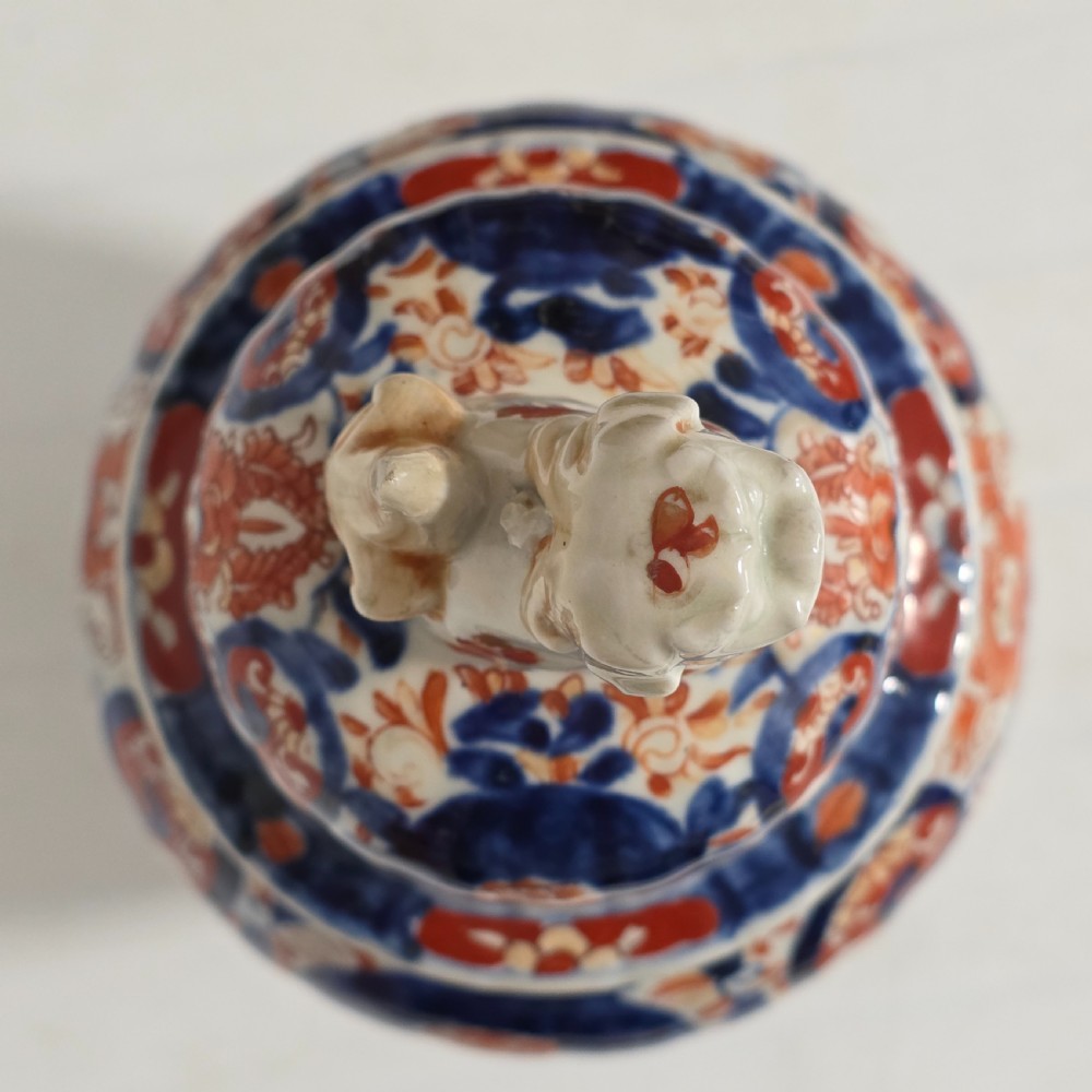 A 19th-century Japanese Imari porcelain covered jar decorated with cobalt blue and rust red floral panel motifs, topped with a sculpted foo dog finial lid. View VIII