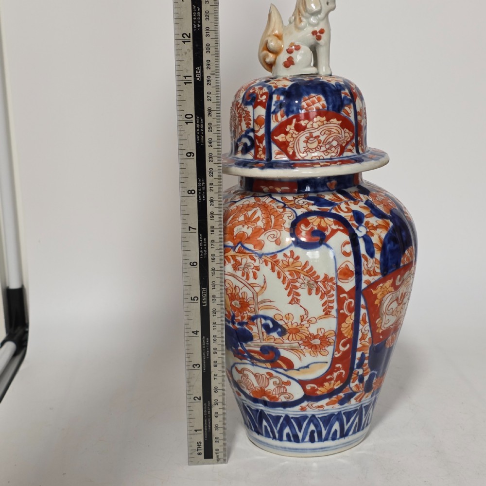 A 19th-century Japanese Imari porcelain covered jar decorated with cobalt blue and rust red floral panel motifs, topped with a sculpted foo dog finial lid. View XII