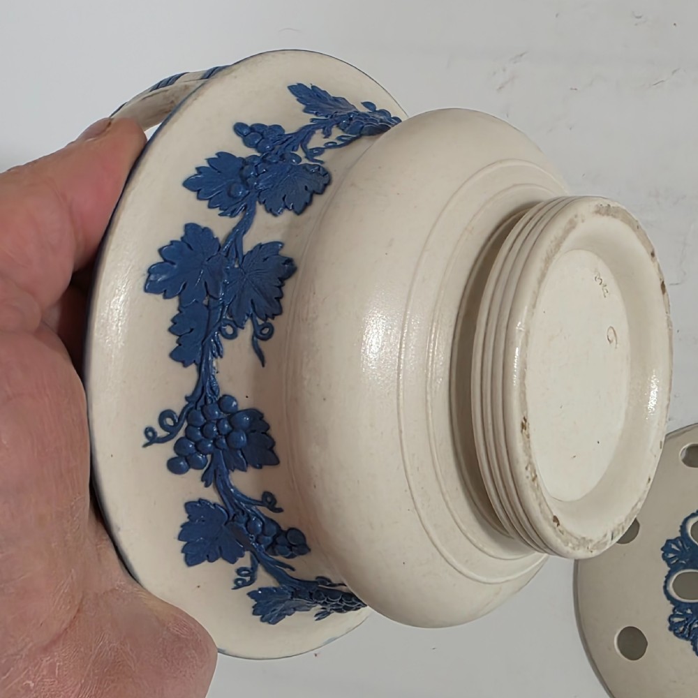 An off-white Georgian stoneware pot pourri basket featuring an overhead handle, pierced cover, and cobalt blue applied grapevine sprig decoration. View VIII