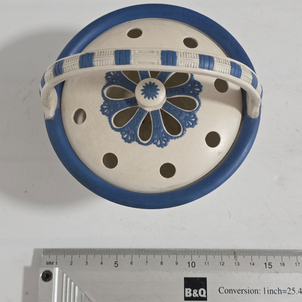 An off-white Georgian stoneware pot pourri basket featuring an overhead handle, pierced cover, and cobalt blue applied grapevine sprig decoration. View X