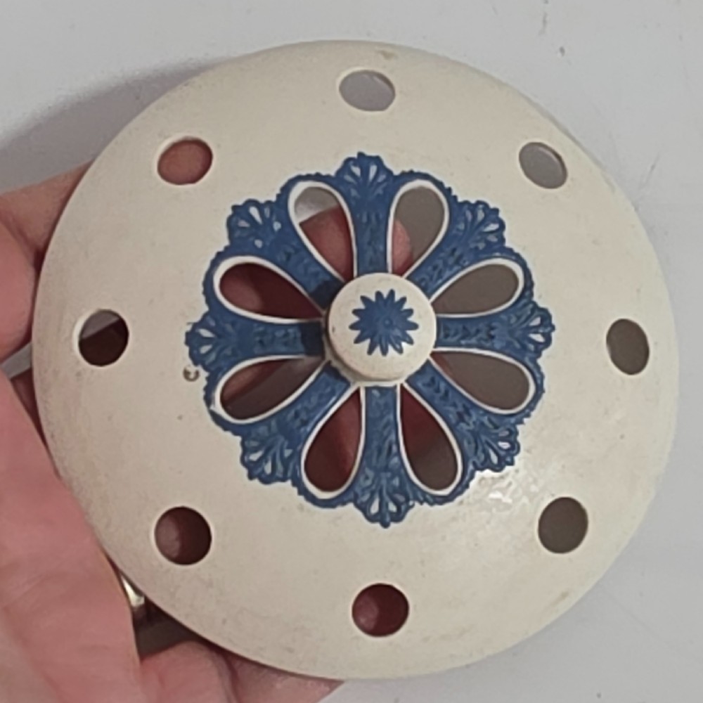 An off-white Georgian stoneware pot pourri basket featuring an overhead handle, pierced cover, and cobalt blue applied grapevine sprig decoration. View XV