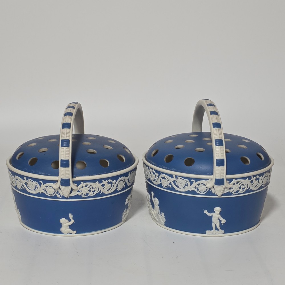 A pair of blue and white Georgian ceramic pot pourri baskets with pierced lids, white classical cherub reliefs, and overhead handles. View II