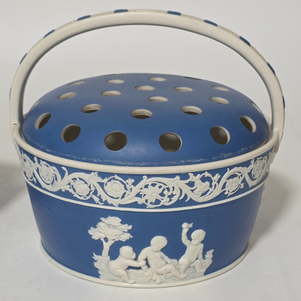 A pair of blue and white Georgian ceramic pot pourri baskets with pierced lids, white classical cherub reliefs, and overhead handles. View III
