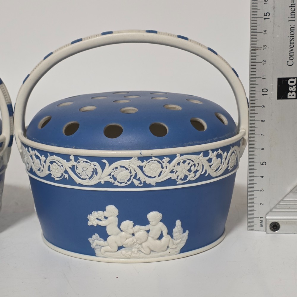 A pair of blue and white Georgian ceramic pot pourri baskets with pierced lids, white classical cherub reliefs, and overhead handles. View VI