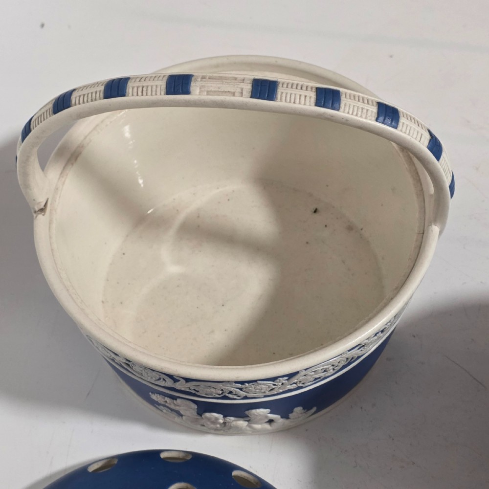 A pair of blue and white Georgian ceramic pot pourri baskets with pierced lids, white classical cherub reliefs, and overhead handles. View IX