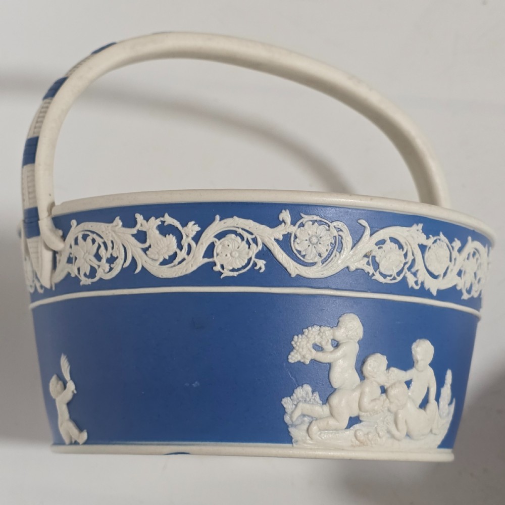 A pair of blue and white Georgian ceramic pot pourri baskets with pierced lids, white classical cherub reliefs, and overhead handles. View X