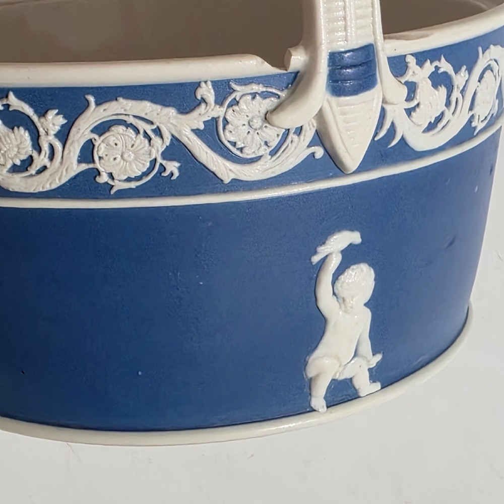 A pair of blue and white Georgian ceramic pot pourri baskets with pierced lids, white classical cherub reliefs, and overhead handles. View XI