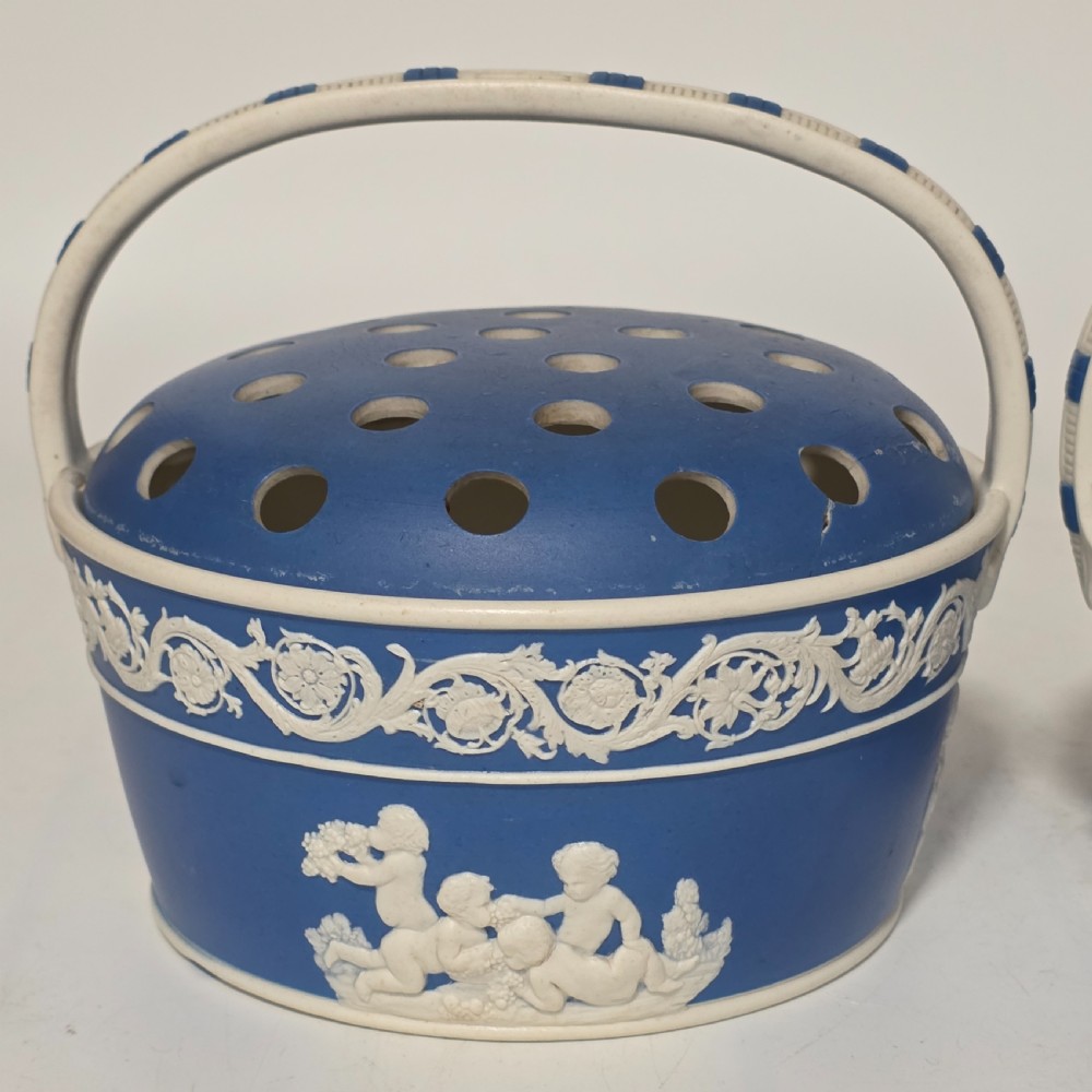 A pair of blue and white Georgian ceramic pot pourri baskets with pierced lids, white classical cherub reliefs, and overhead handles. View XV