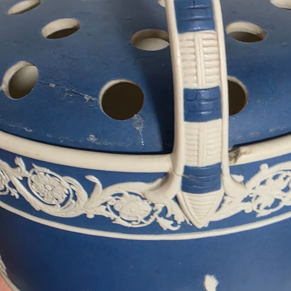 A pair of blue and white Georgian ceramic pot pourri baskets with pierced lids, white classical cherub reliefs, and overhead handles. View XXVI