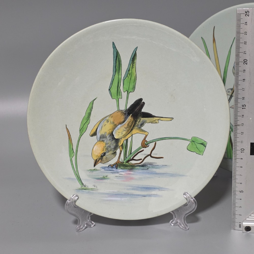 A pair of circular pale green ceramic display plates hand painted with detailed birds near water lilies and reeds. View VI