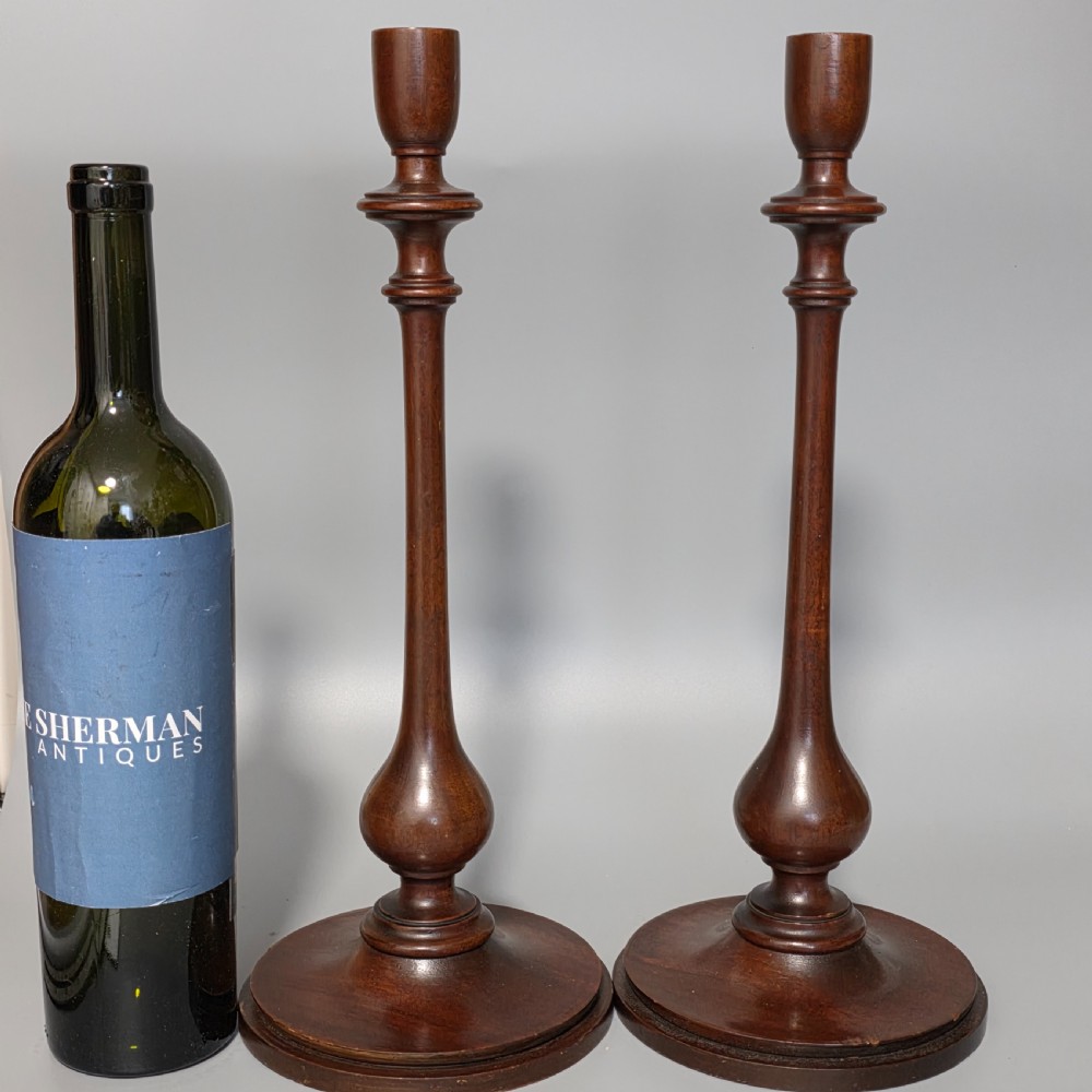 A pair of tall turned dark wood candlesticks featuring bulbous lower shafts and circular stepped bases. View II