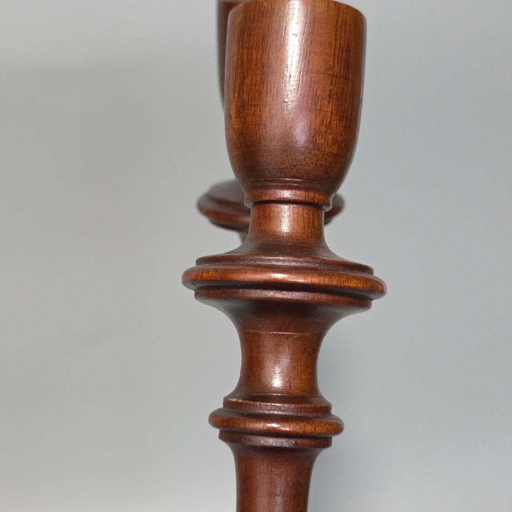 A pair of tall turned dark wood candlesticks featuring bulbous lower shafts and circular stepped bases. View V