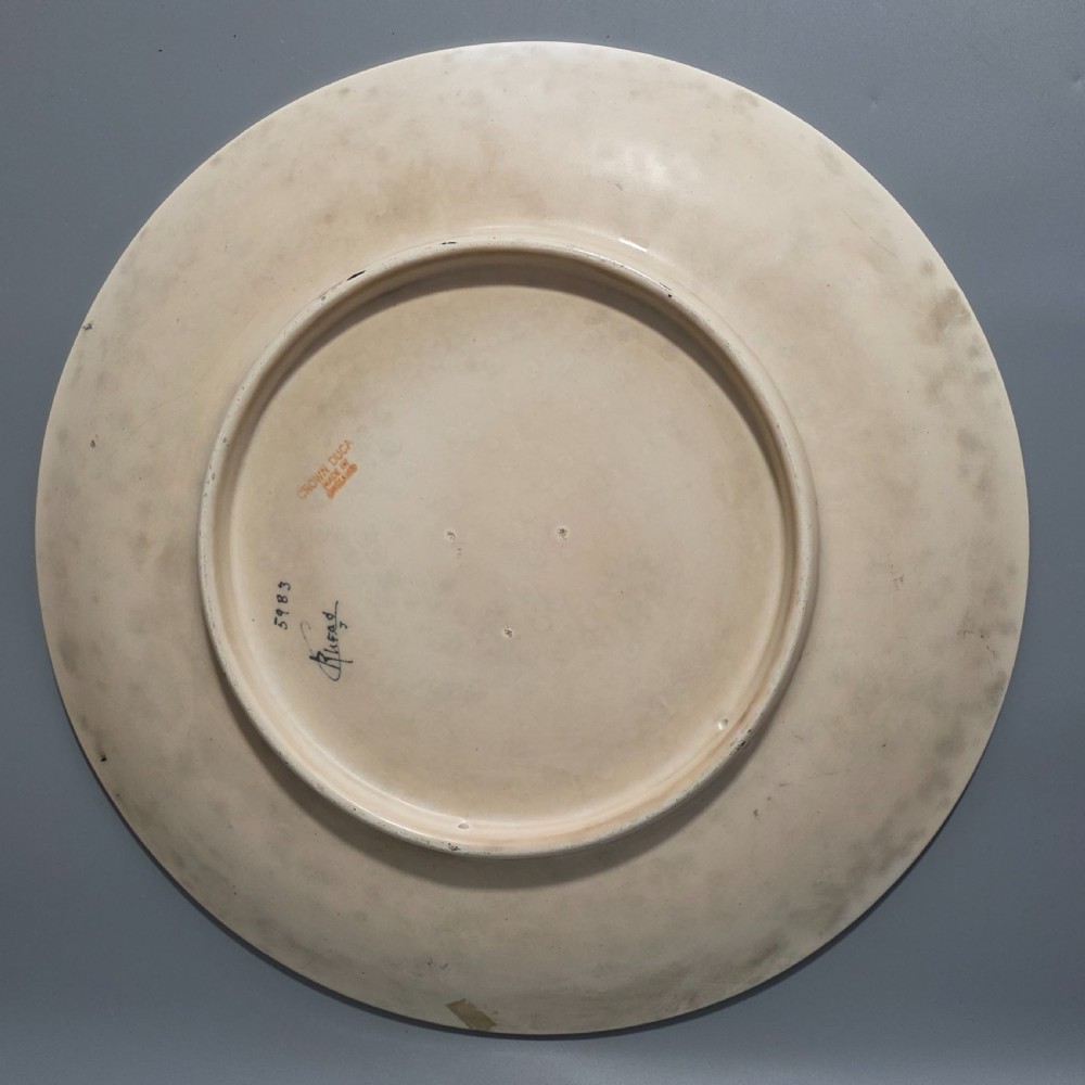 A circular Art Deco earthenware charger decorated with pink, orange, yellow, and blue stylised floral tubelined motifs. View VII