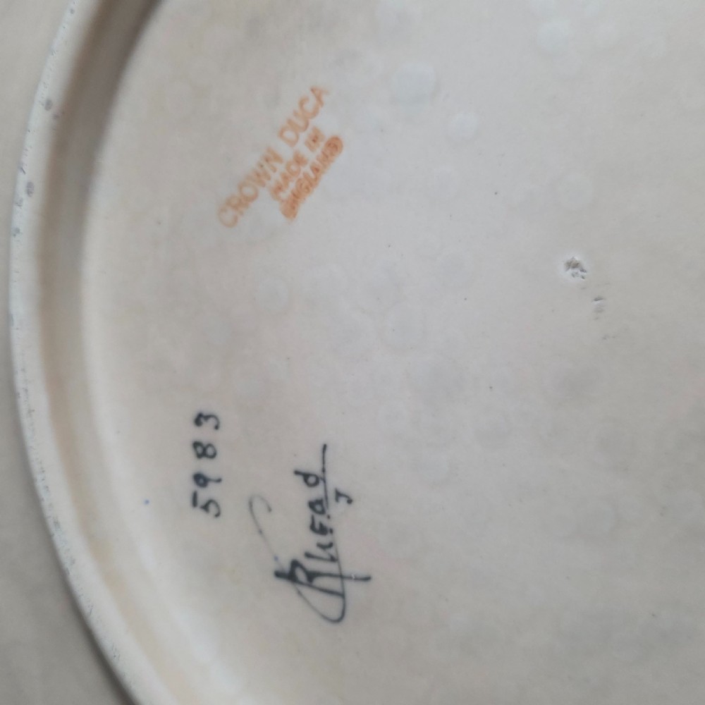 A circular Art Deco earthenware charger decorated with pink, orange, yellow, and blue stylised floral tubelined motifs. View VIII