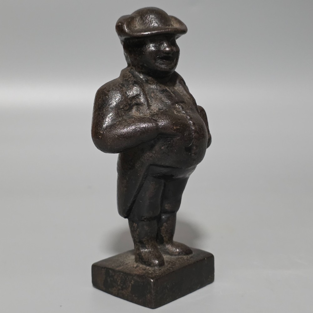 A dark cast iron paperweight depicting a standing nineteenth-century gentleman on a square plinth base. View II
