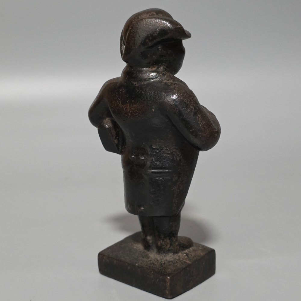 A dark cast iron paperweight depicting a standing nineteenth-century gentleman on a square plinth base. View III