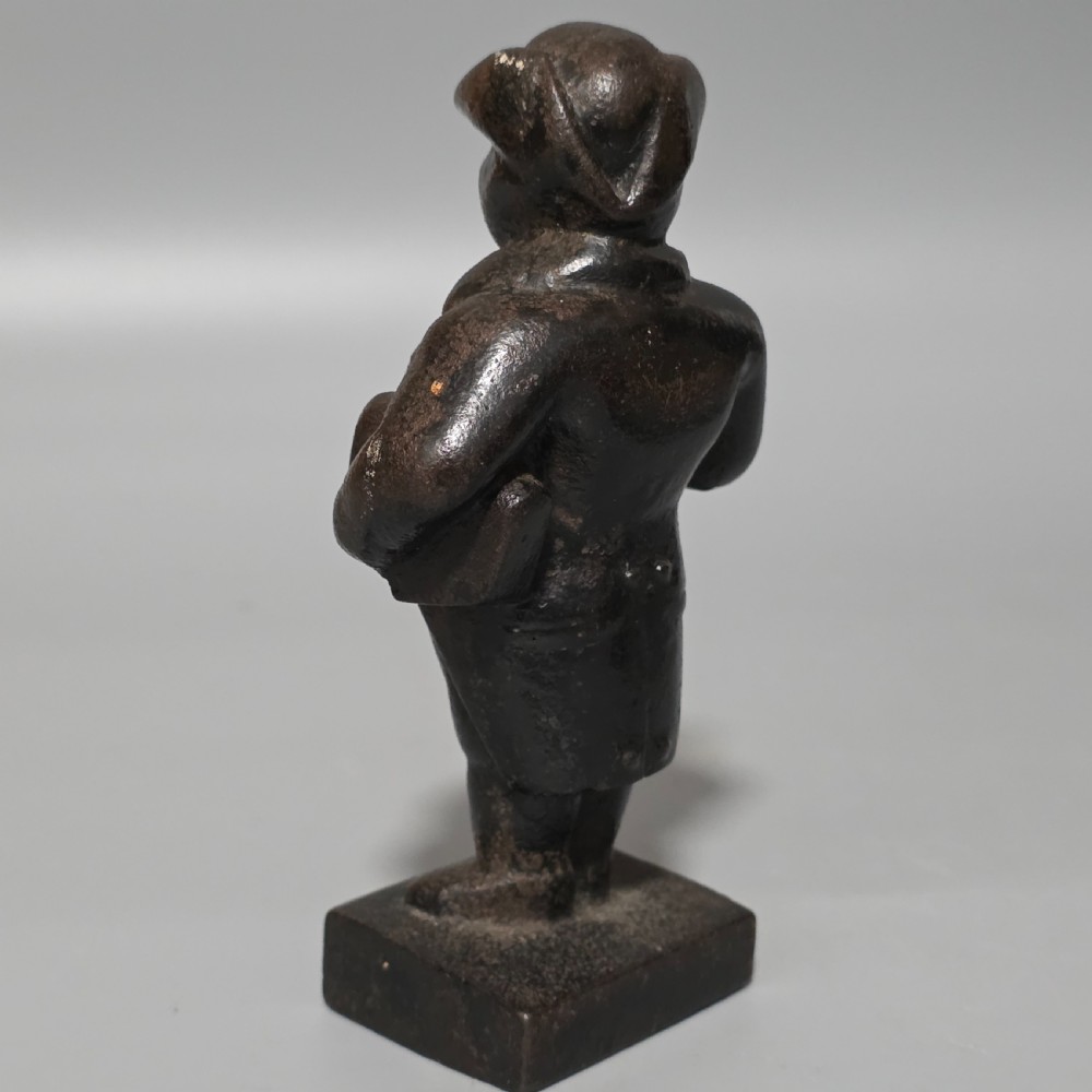 A dark cast iron paperweight depicting a standing nineteenth-century gentleman on a square plinth base. View IV
