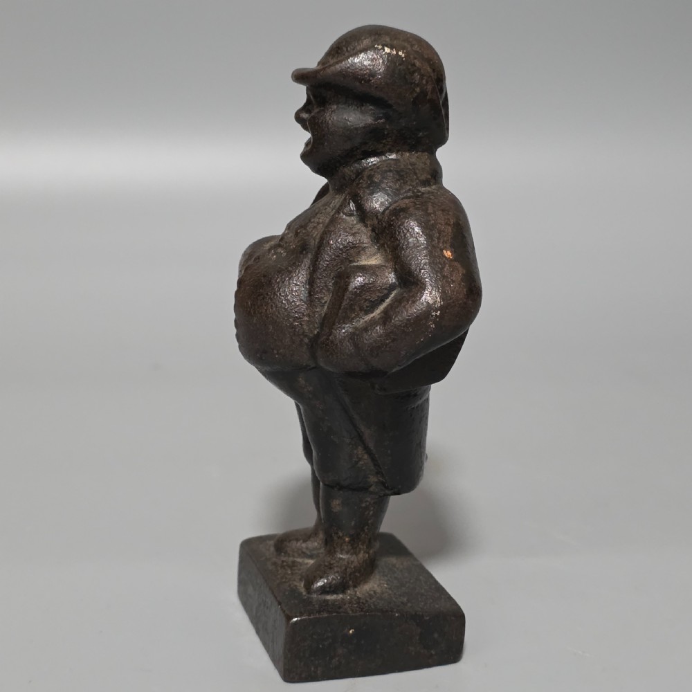 A dark cast iron paperweight depicting a standing nineteenth-century gentleman on a square plinth base. View V