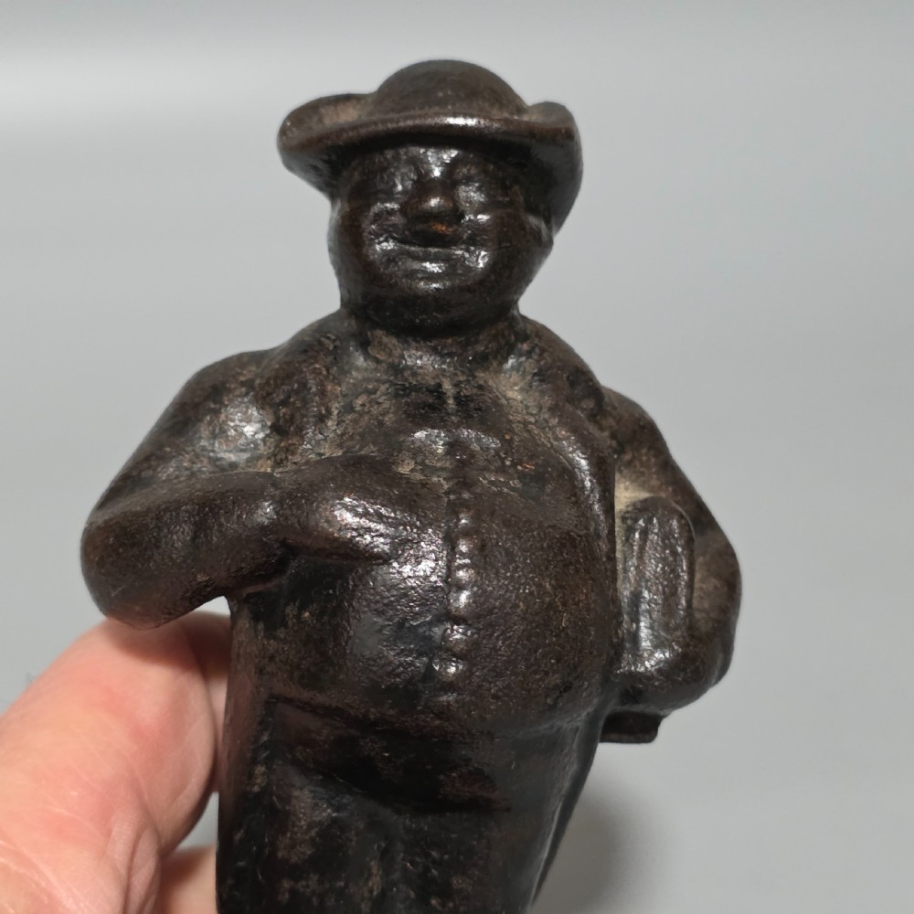 A dark cast iron paperweight depicting a standing nineteenth-century gentleman on a square plinth base. View VI