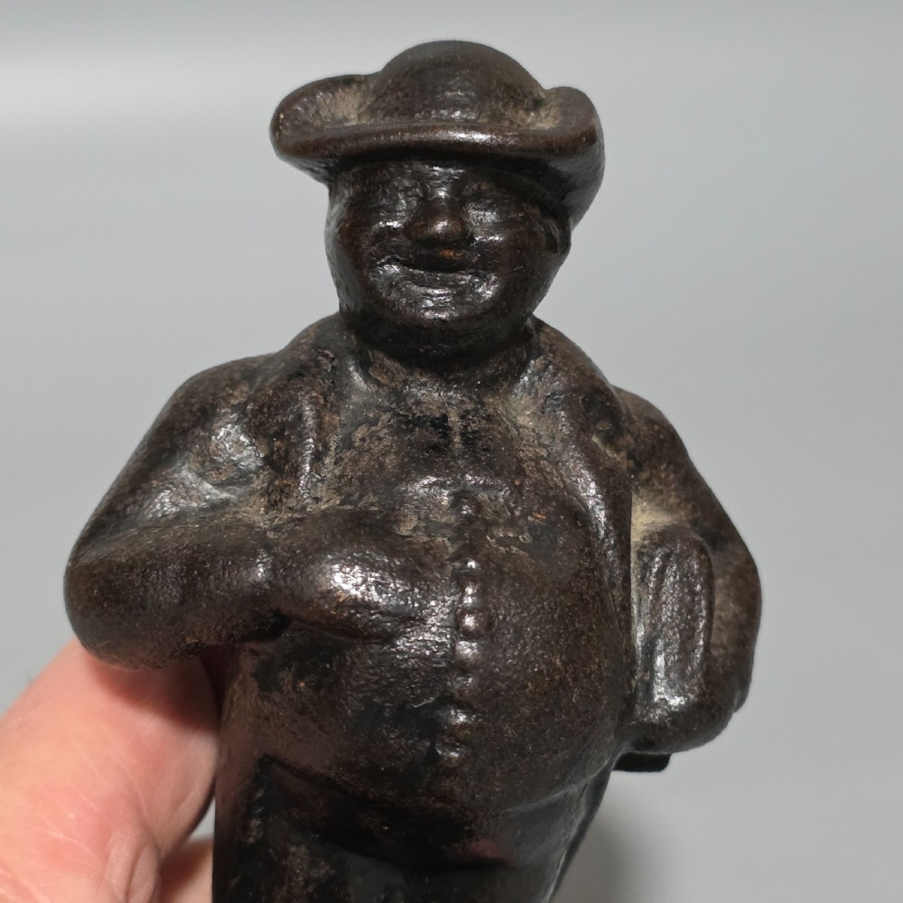 A dark cast iron paperweight depicting a standing nineteenth-century gentleman on a square plinth base. View VII